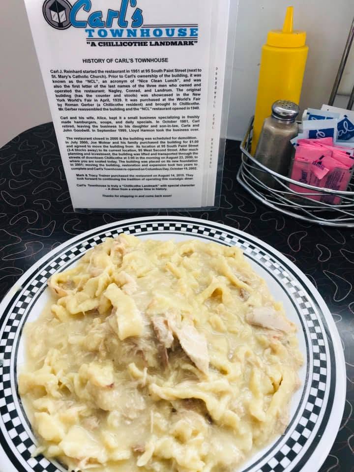 The history of Carl's Townhouse, printed on a card at the table, next to a plate of homemade chicken and noodles